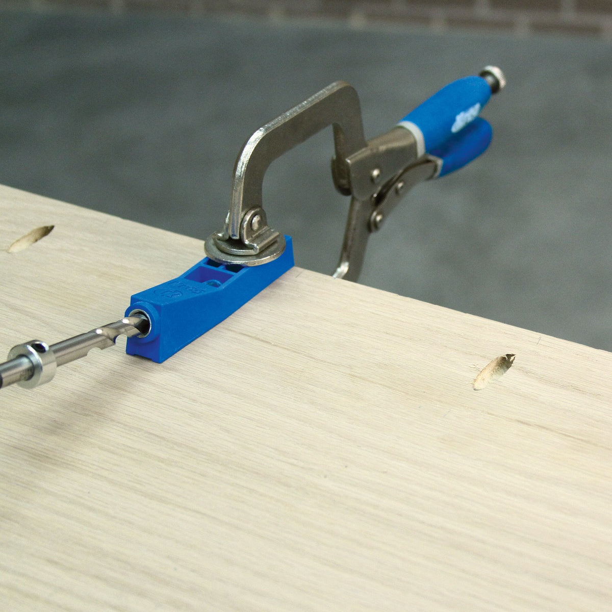 Kreg Tool MKJKIT Mini Jig Kit clamped to a wood board while drilling a pocket hole for furniture repair or joinery work