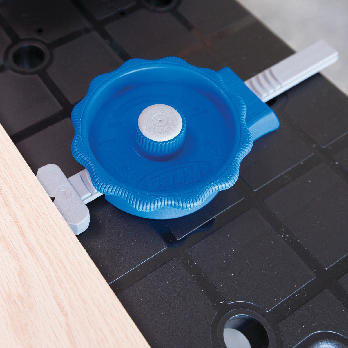 Kreg KBCIC In-Line Clamp installed in a portable work surface dog hole holding a wood panel for bench work