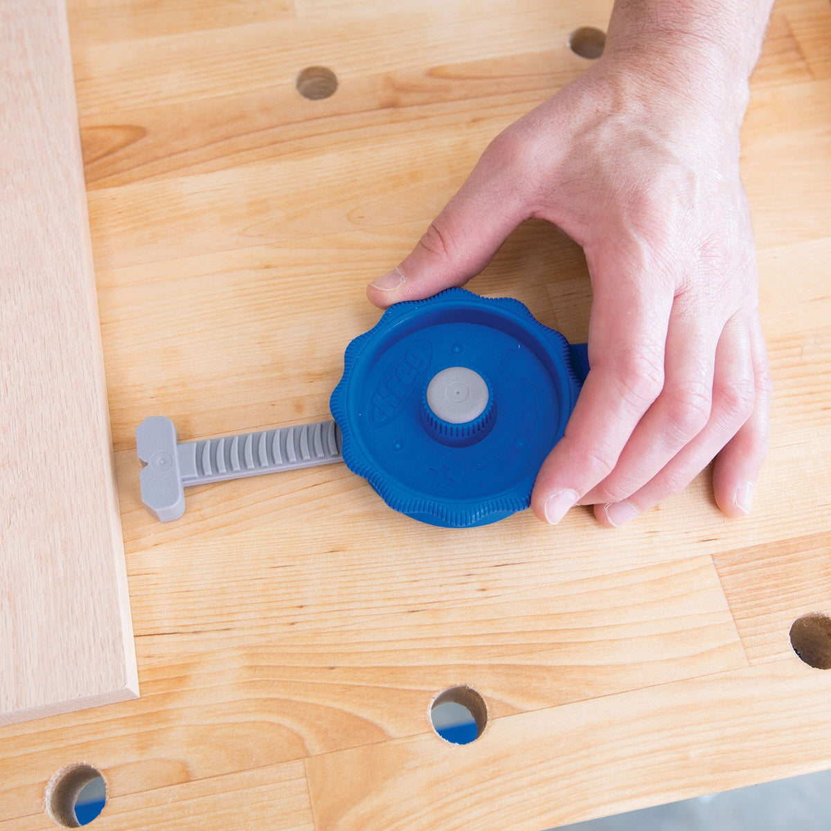 Kreg KBCIC In-Line Clamp securing a woodworking board on a bench with 3/4 inch dog holes during assembly work