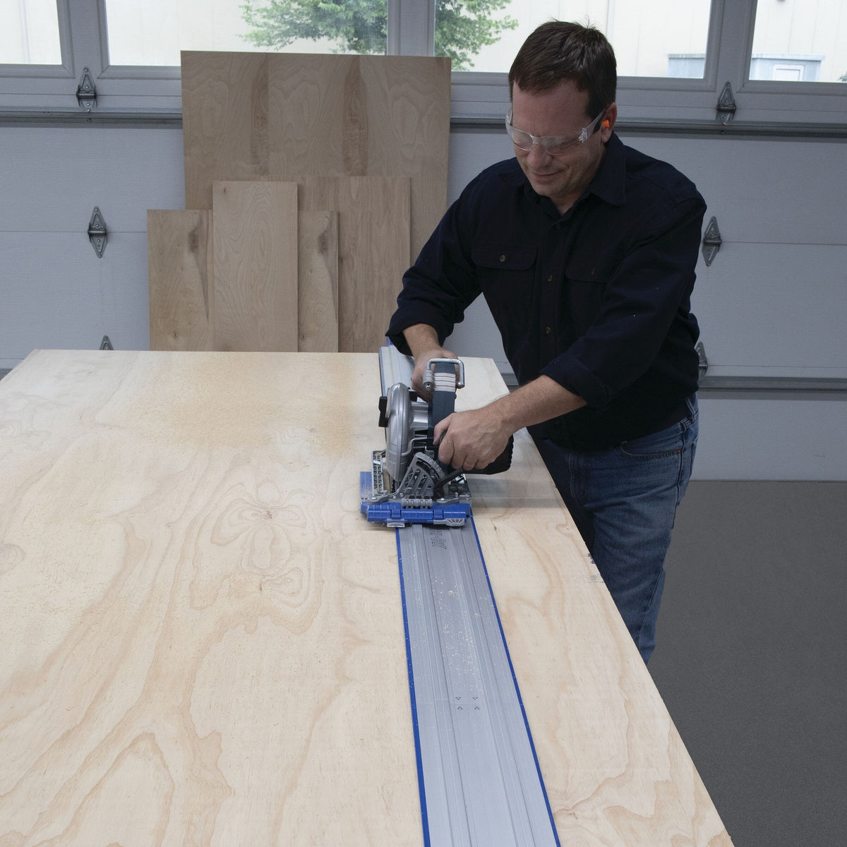 Kreg KMA2750 Accu-Cut Expansion Pack used with a circular saw to cut a large plywood panel on a bench