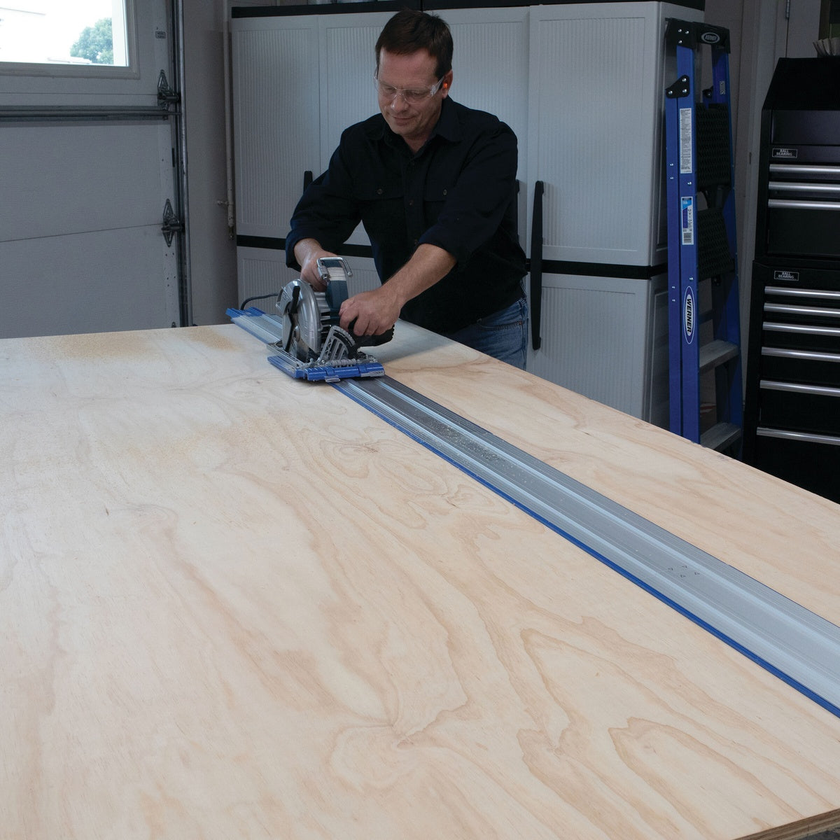 Kreg KMA2750 Accu-Cut Expansion Pack guiding a circular saw through a long plywood sheet cut in a workshop setting