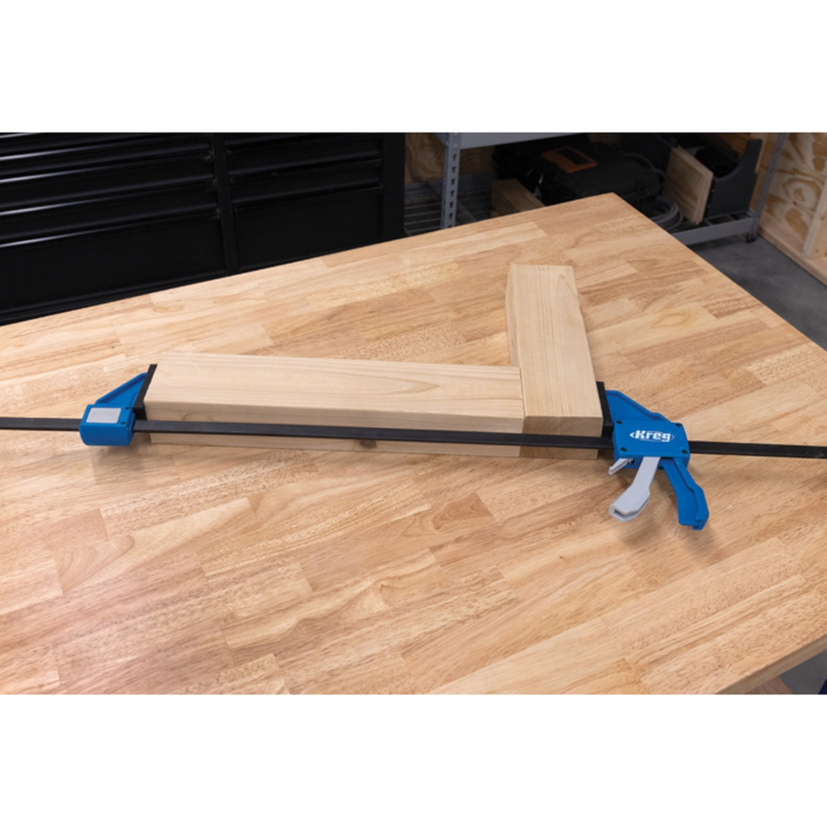Kreg Tool KVGC36 36 in. VersaGrip Clamp holding wood boards during a woodworking glue-up on a workbench