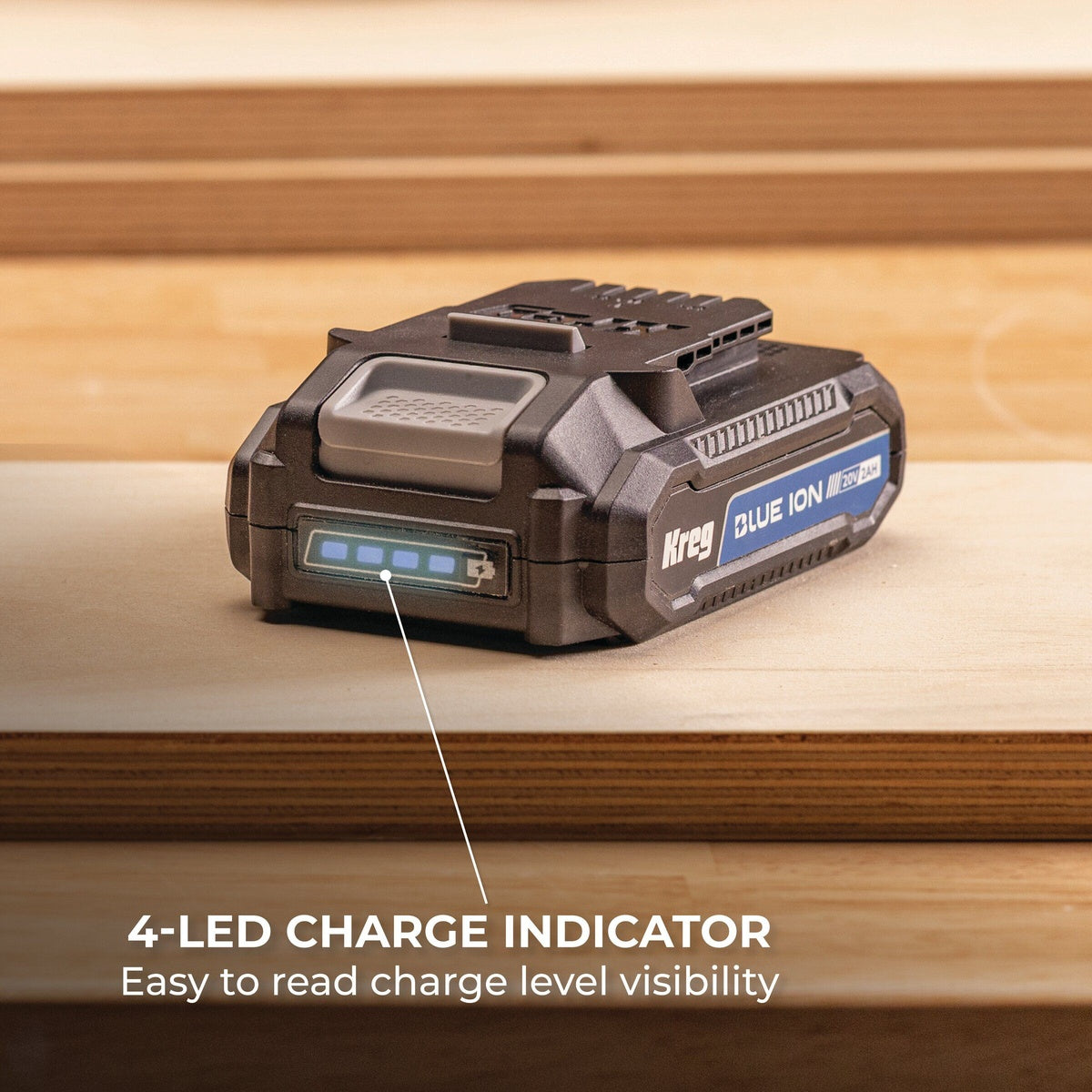 Kreg 20V Blue Ion 2.0 Ah battery pack resting on plywood with the four LED fuel gauge visible in a workshop setting