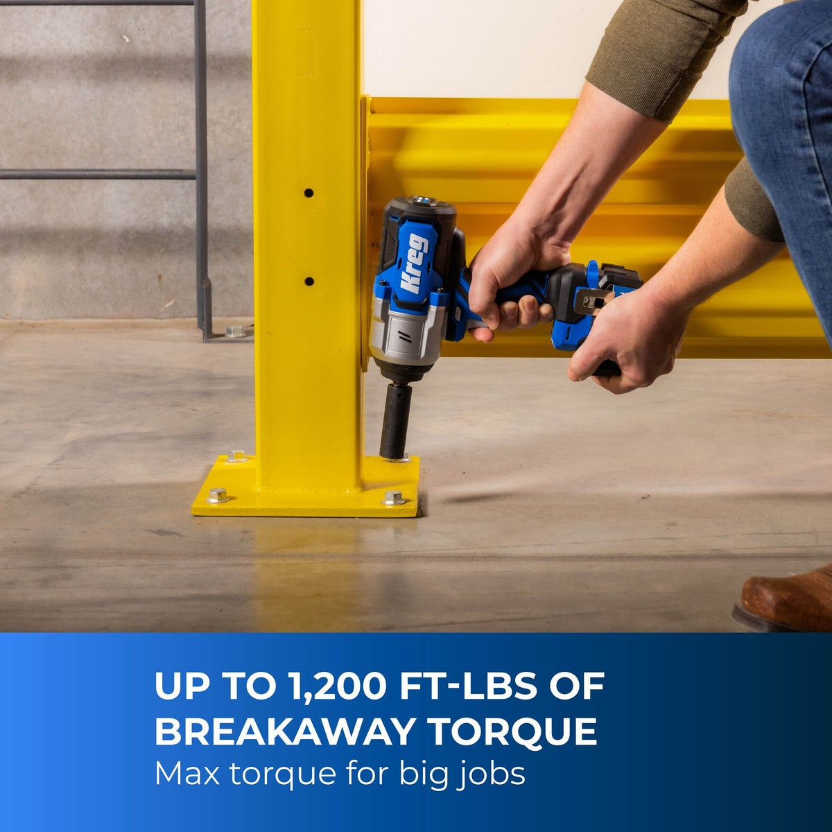 Kreg 20V Ionic Drive High Torque 1/2 inch Impact Wrench removing heavy anchor hardware at a steel post base on a concrete floor in a workshop