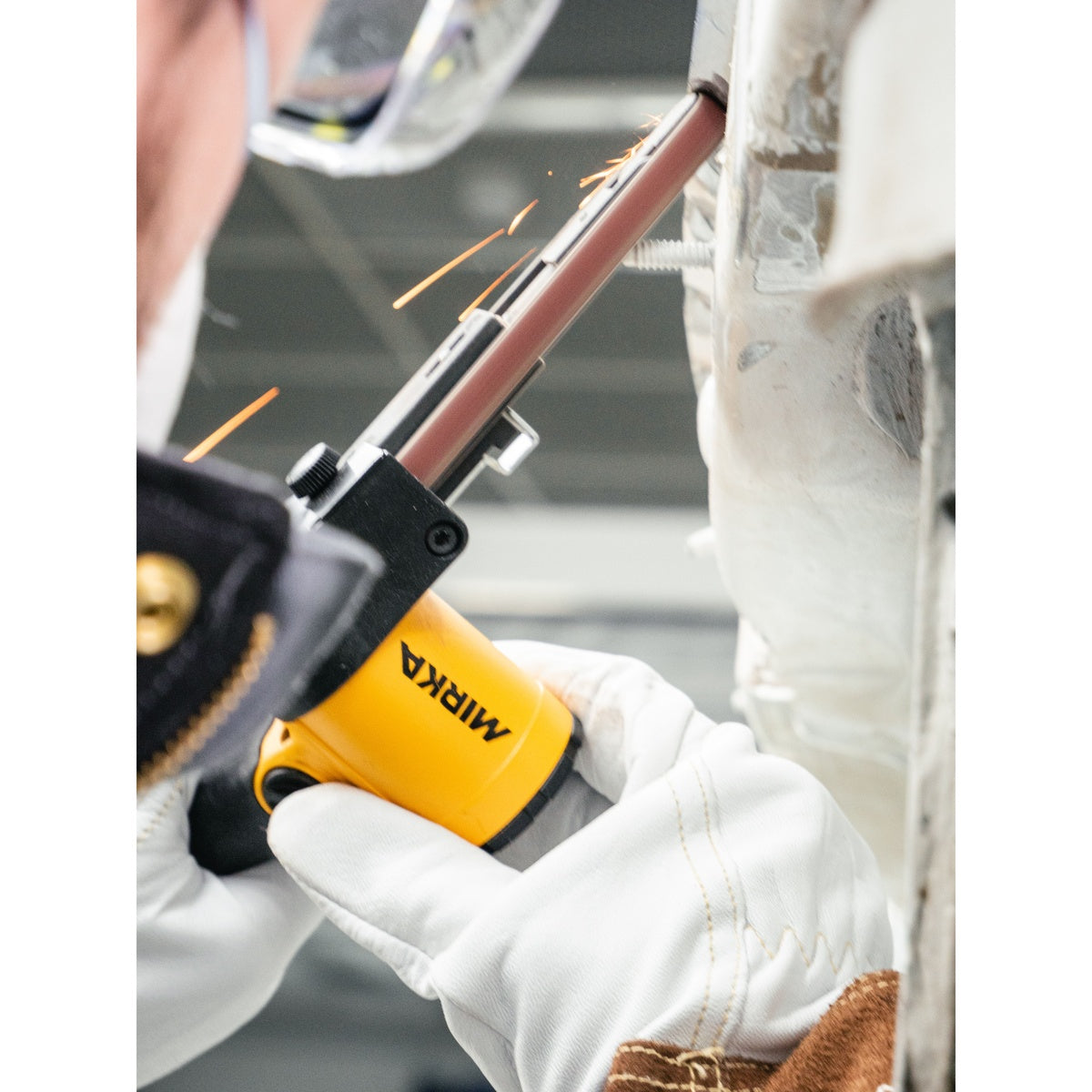 Close-up of Mirka PBS belt sander grinding a weld area on sheet metal