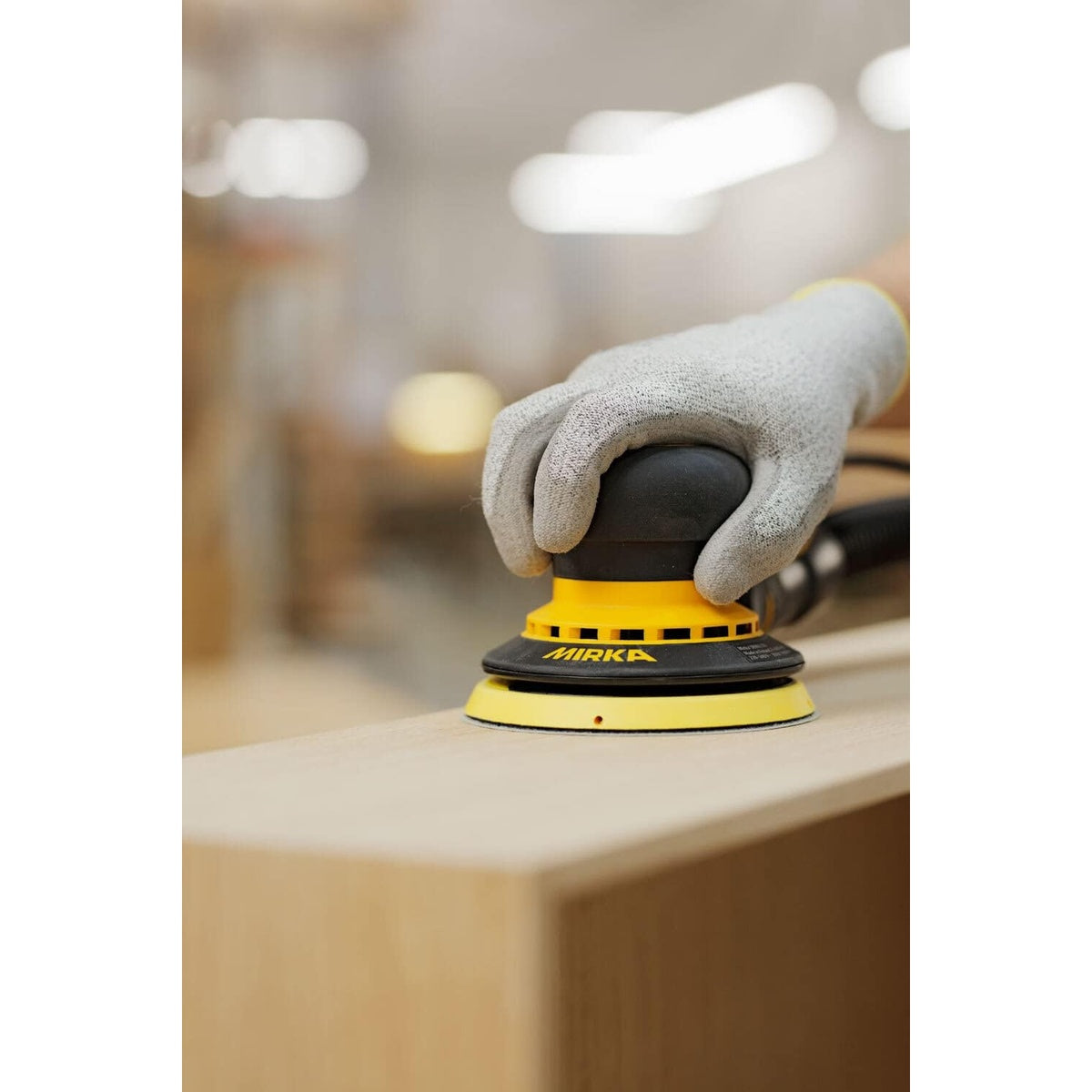 Mirka DEROS 550CV random orbital sander in use on a wood surface