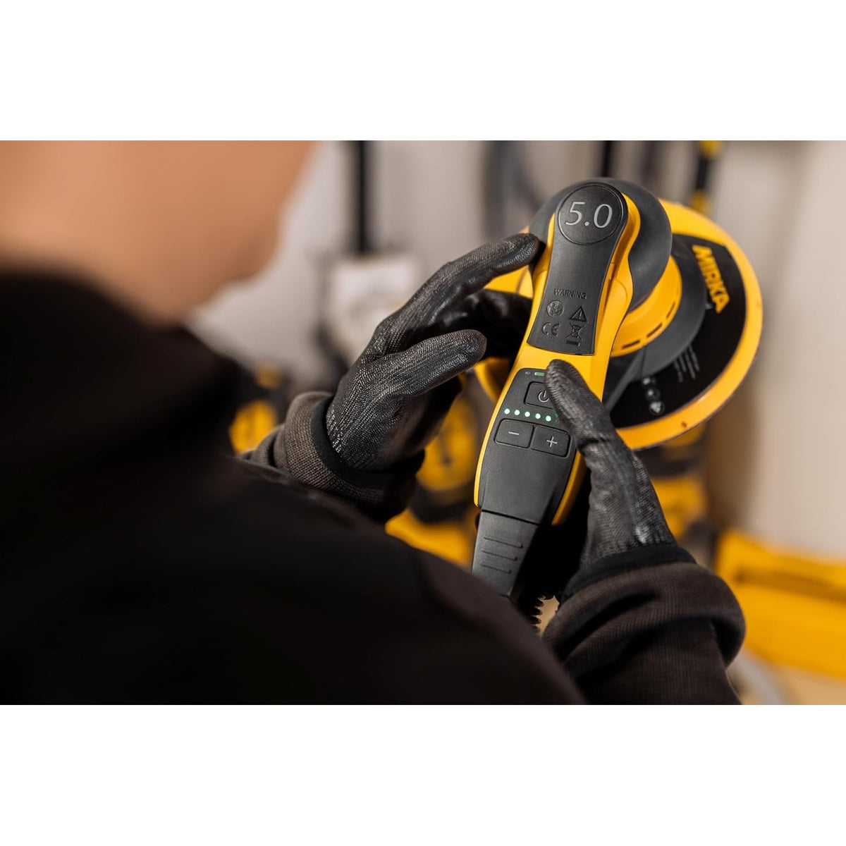 Operator adjusting speed controls on Mirka DEROS II random orbital sander