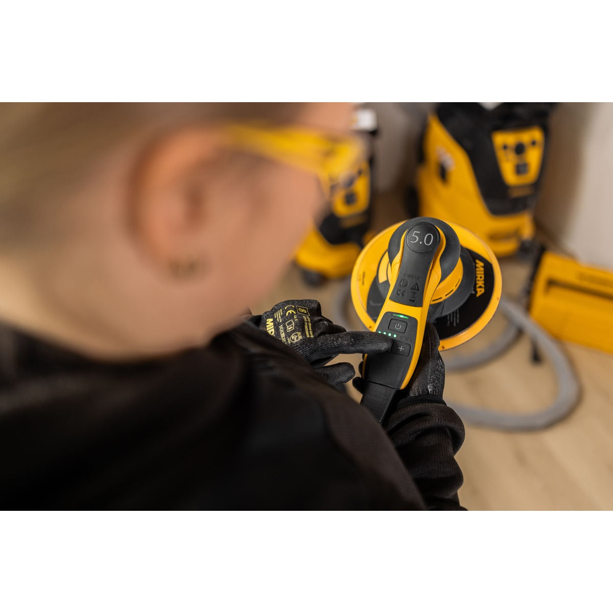 Mirka DEROS II 750X random orbital sander in use showing top controls and 5.0 mm orbit cap