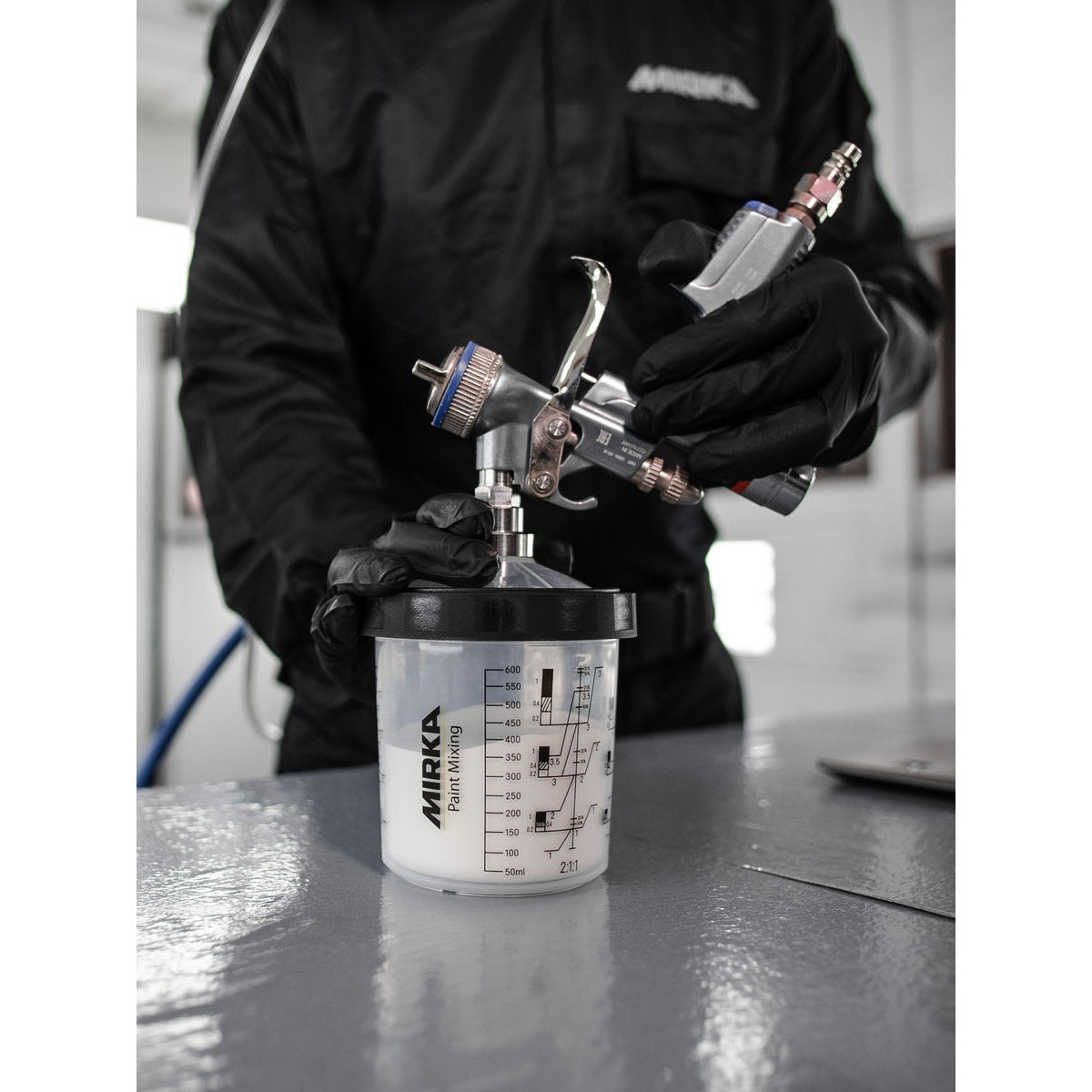 Mirka paint mixing cup system connected to a spray gun with stainless steel adapter