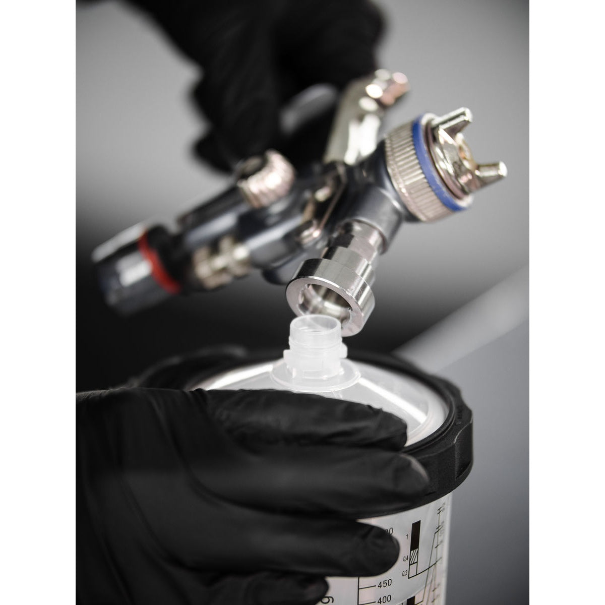 Close-up of Mirka spray gun adapter aligning with paint cup lid connector