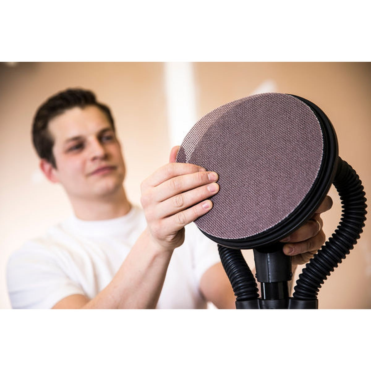 Worker applying Mirka Abranet Ace sanding disc to a Mirka LEROS sander head