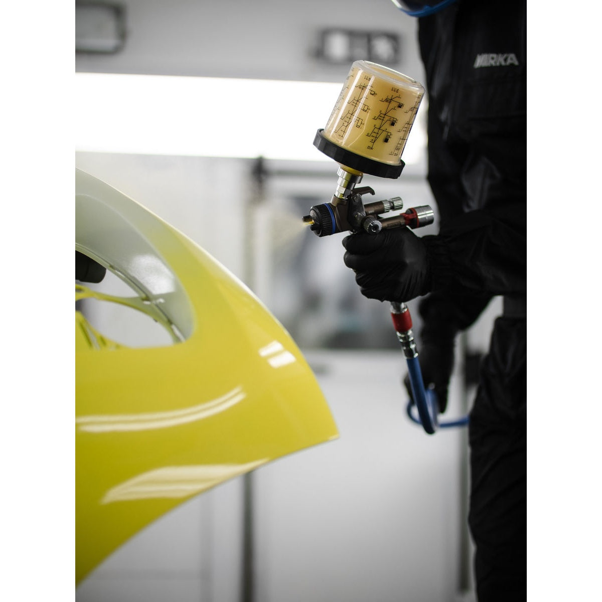 Mirka paint cup system attached to a spray gun during automotive painting