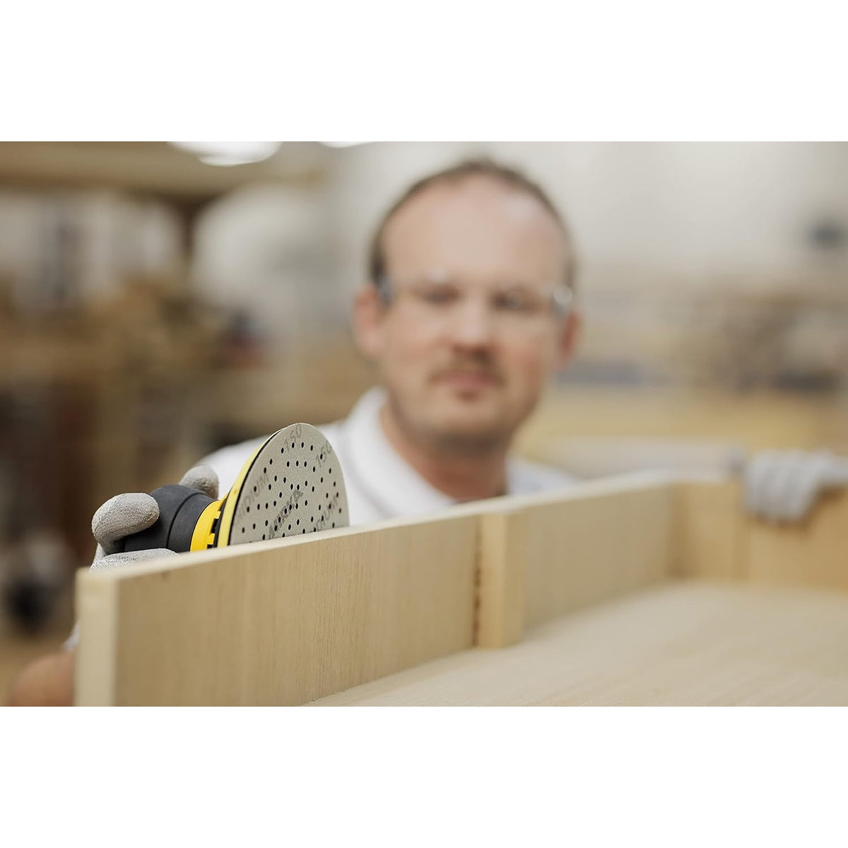 Orbital sander using a Mirka multihole sanding disc on a wood panel