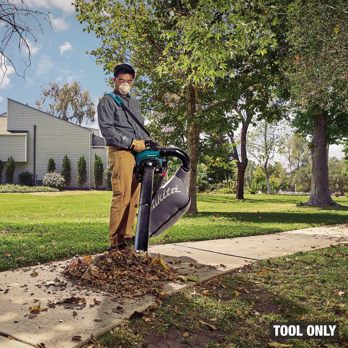 Makita GBU03ZV cordless blower in vacuum mode picking up leaves from a sidewalk into the collection bag